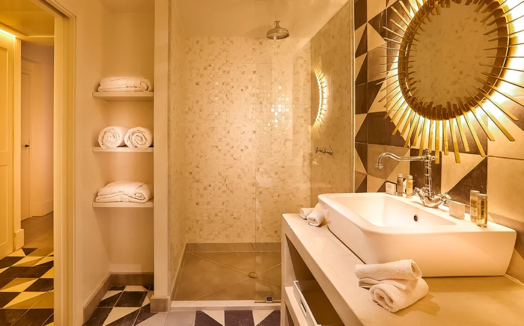 Baño de la habitación Charme del hotel 2Ciels Marrakech con ducha de mosaico y espejo dorado