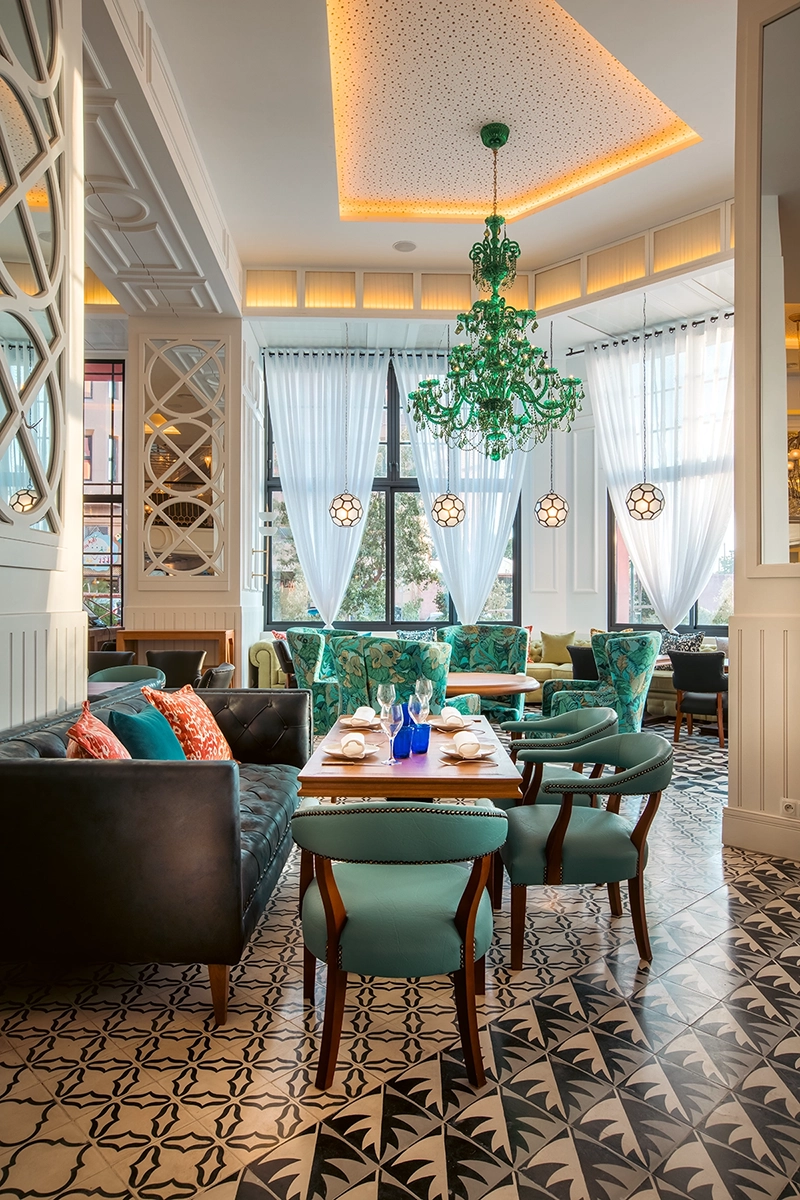 Comedor del hotel 2Ciels Marrakech con lámpara de cristal verde y sillas turquesa