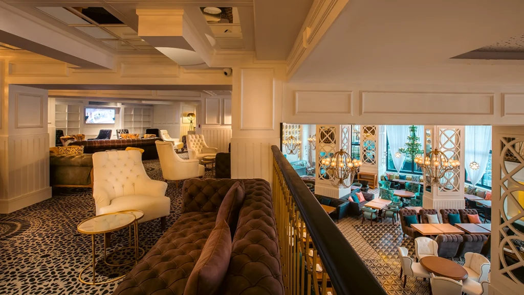 Salón en la entreplanta del hotel 2Ciels Marrakech con lámparas globo doradas sobre el restaurante