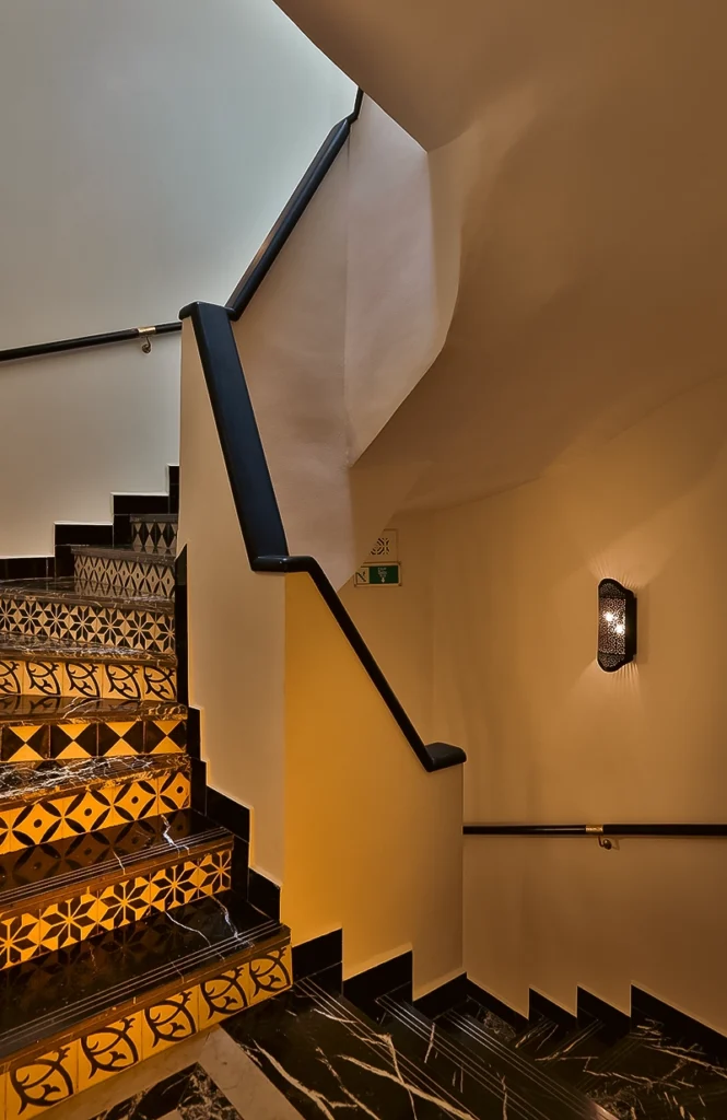 Escalera del hotel 2Ciels Marrakech con contrahuellas de azulejo estampado y peldaños de mármol negro
