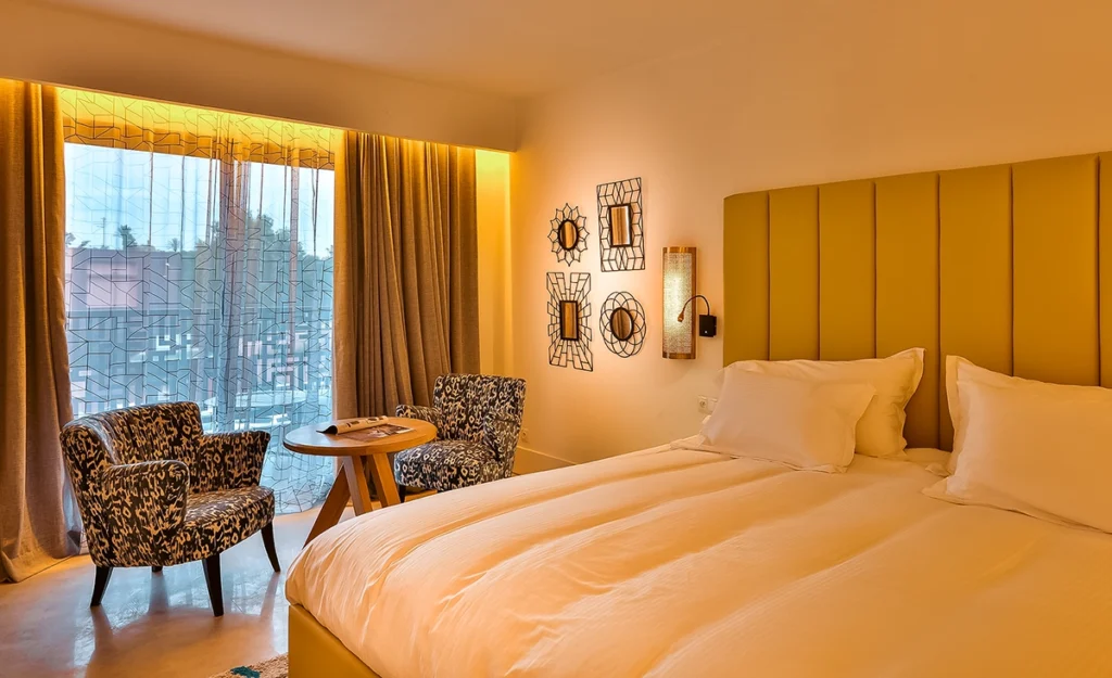 Habitación Charme del hotel 2Ciels Marrakech con cabecero mostaza y butacas junto al balcón