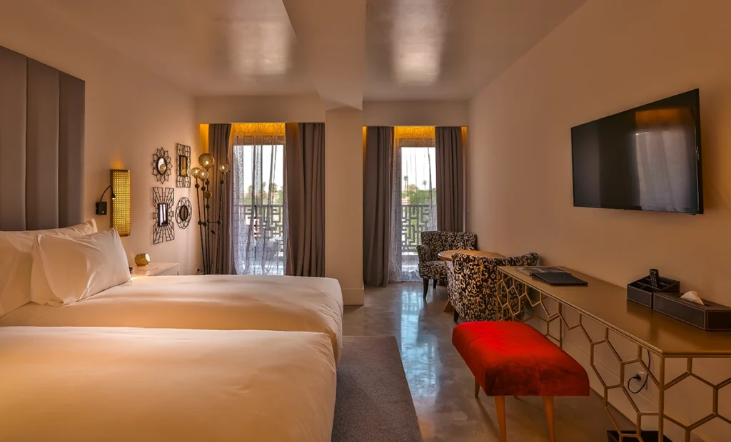 Habitación Charme del hotel 2Ciels Marrakech con banqueta roja y dos ventanales al balcón