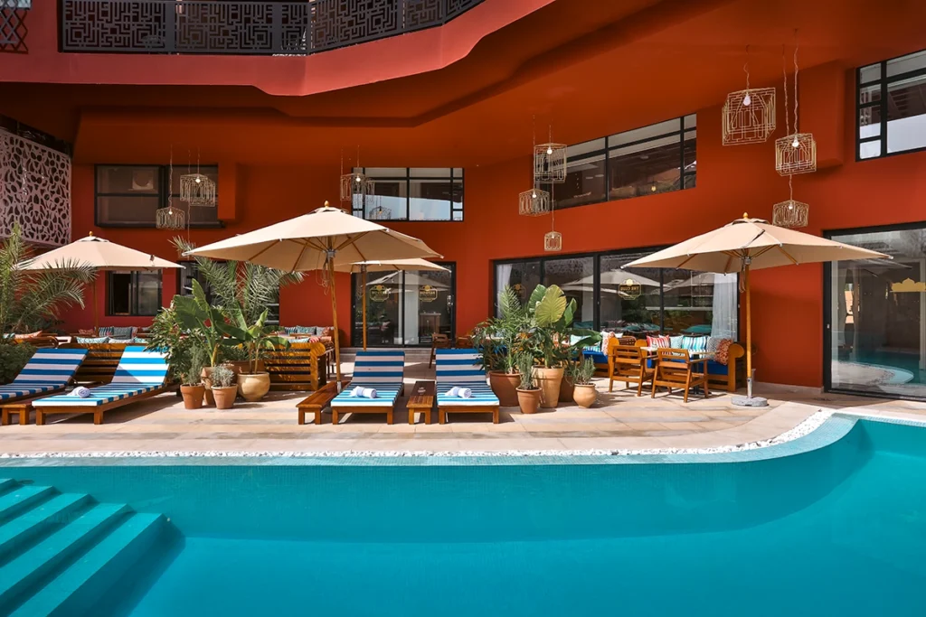 Piscina jardín del hotel 2Ciels Marrakech con tumbonas de rayas azules y sombrillas