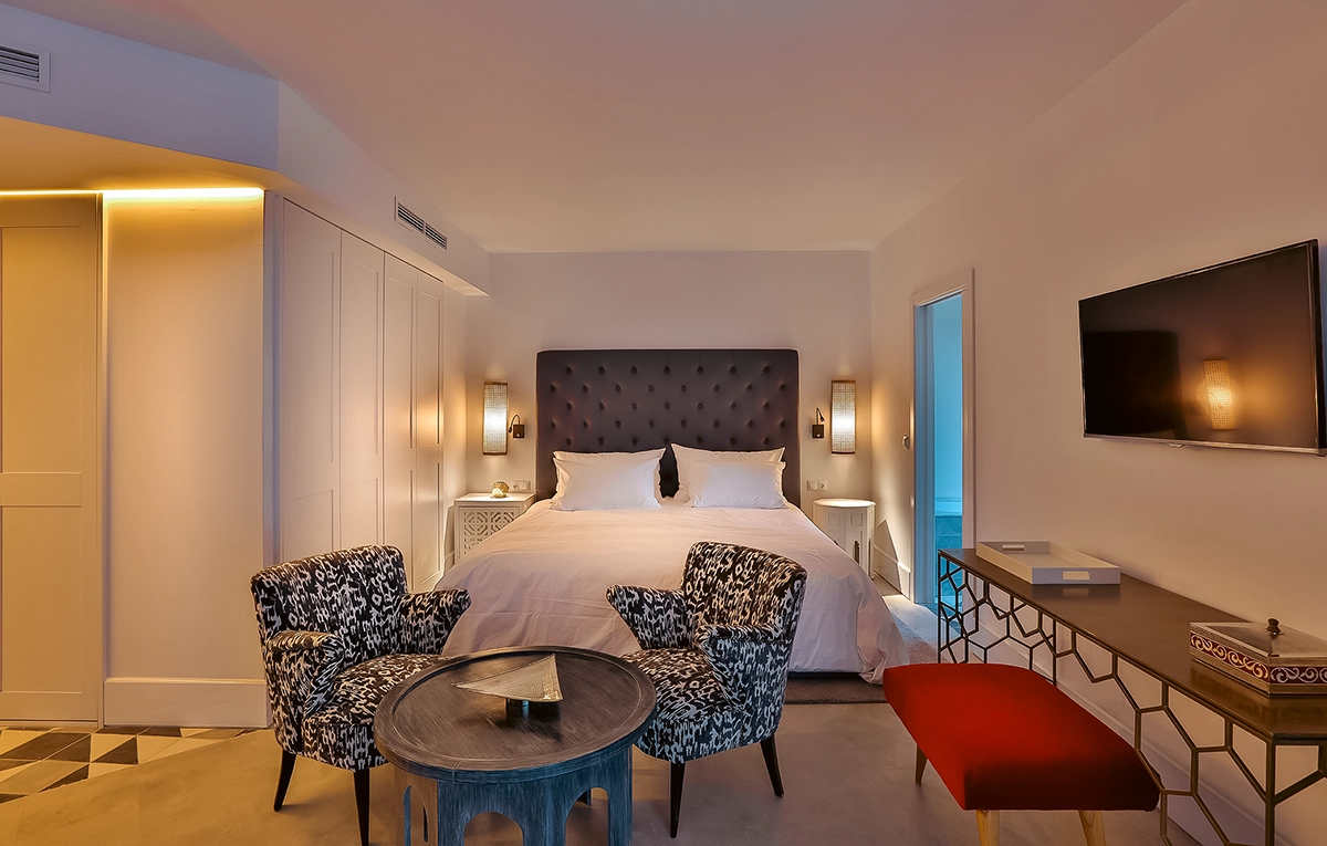 Dormitorio de la Prestige Suite del hotel 2Ciels Marrakech con butacas ikat y escritorio de latón