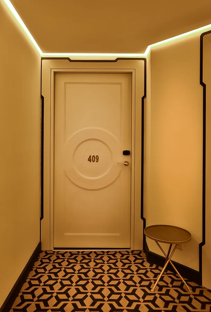 Puerta de habitación del hotel 2Ciels Marrakech en un pasillo Art Déco con moqueta geométrica