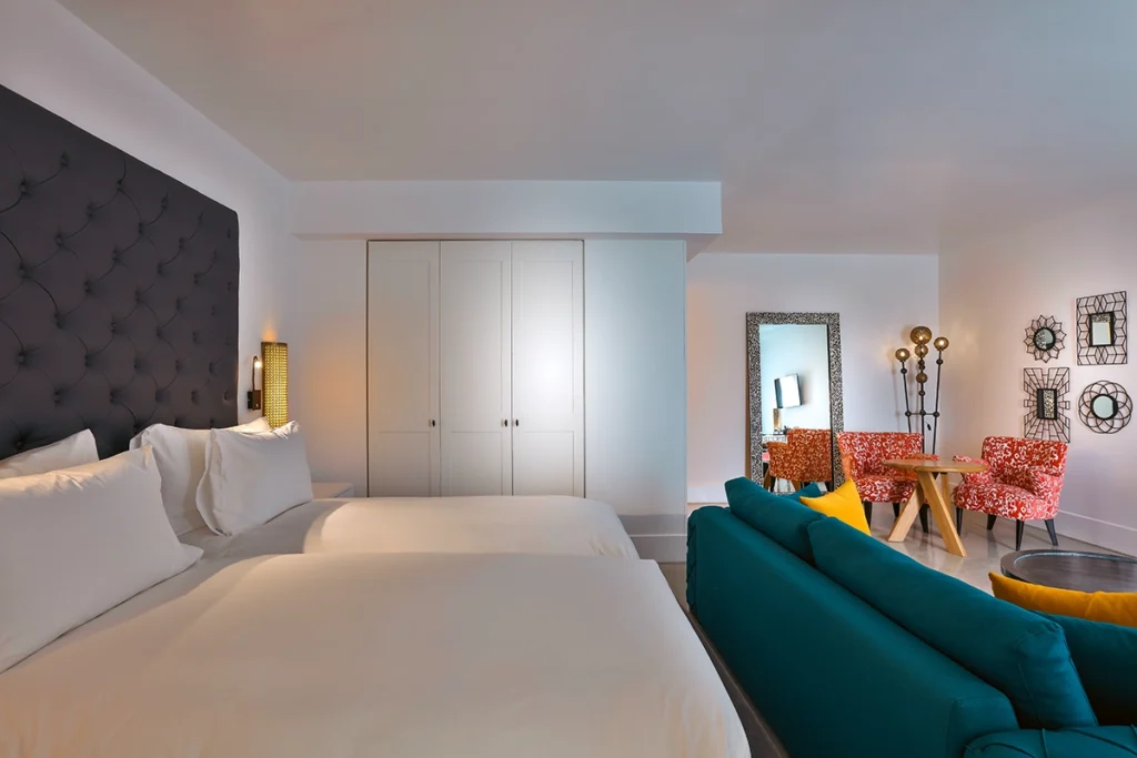 Suite LifeStyle del hotel 2Ciels Marrakech con camas, sofá turquesa y mesa de comedor
