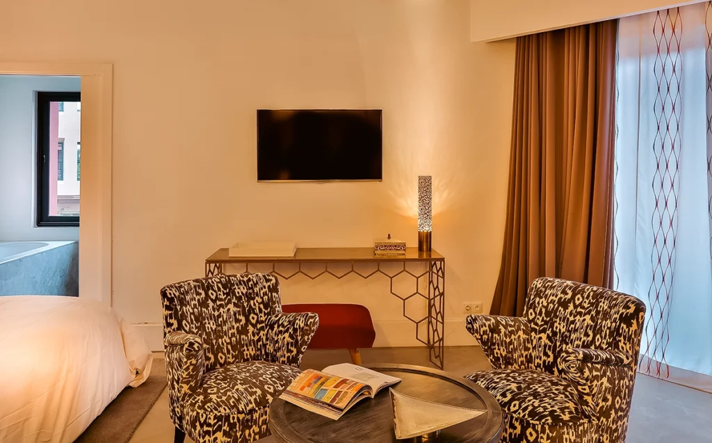 Rincón de estar de la Suite Prestige del hotel 2Ciels Marrakech con butacas ikat y escritorio de latón