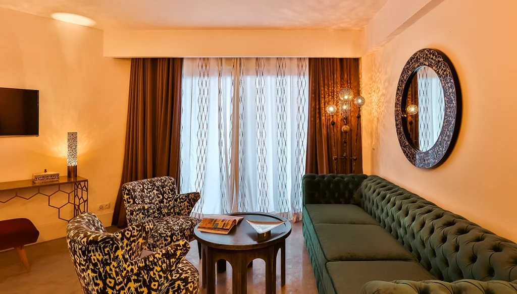 Salón de la Suite Prestige del hotel 2Ciels Marrakech con chesterfield verde y espejo redondo tallado