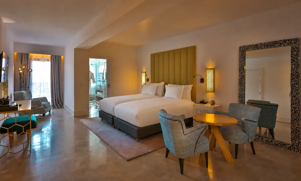 Habitación Deluxe del hotel 2Ciels Marrakech con cabecero verde oliva y dos butacas grises