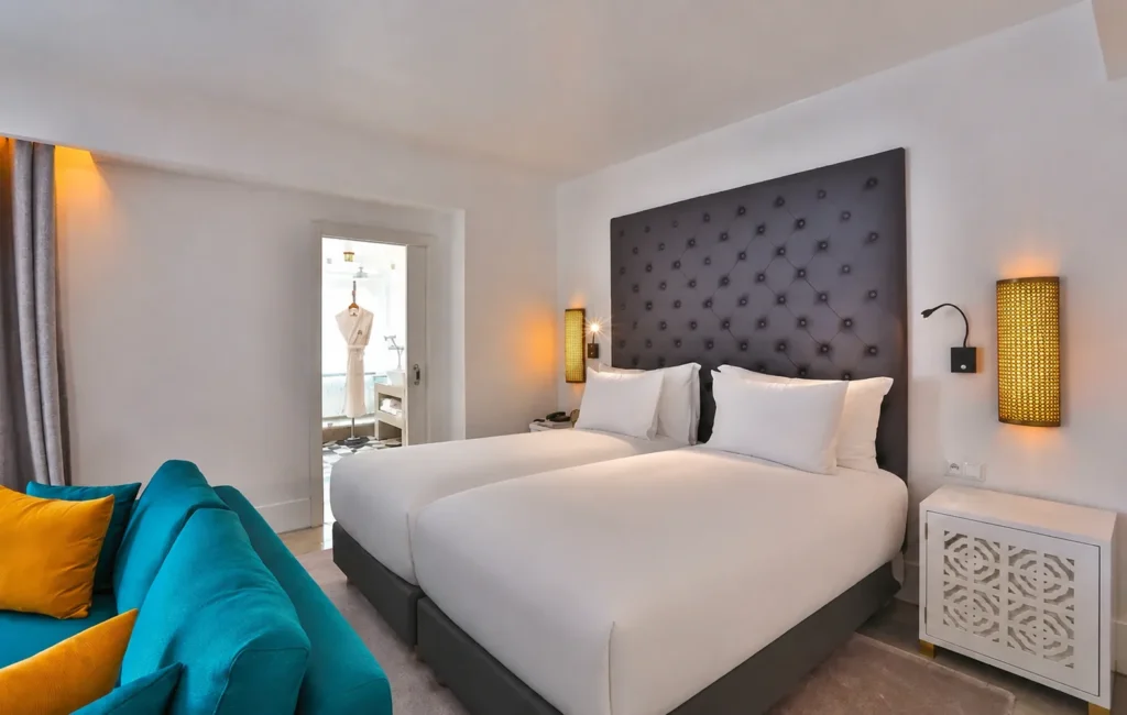 Dormitorio de la Suite LifeStyle del hotel 2Ciels Marrakech con cabecero capitoné y sofá turquesa