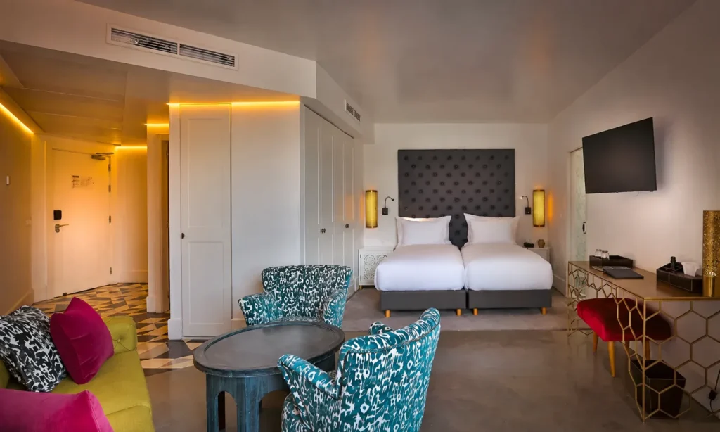 Vista general de la Suite Prestige del hotel 2Ciels Marrakech con camas, butacas ikat y escritorio